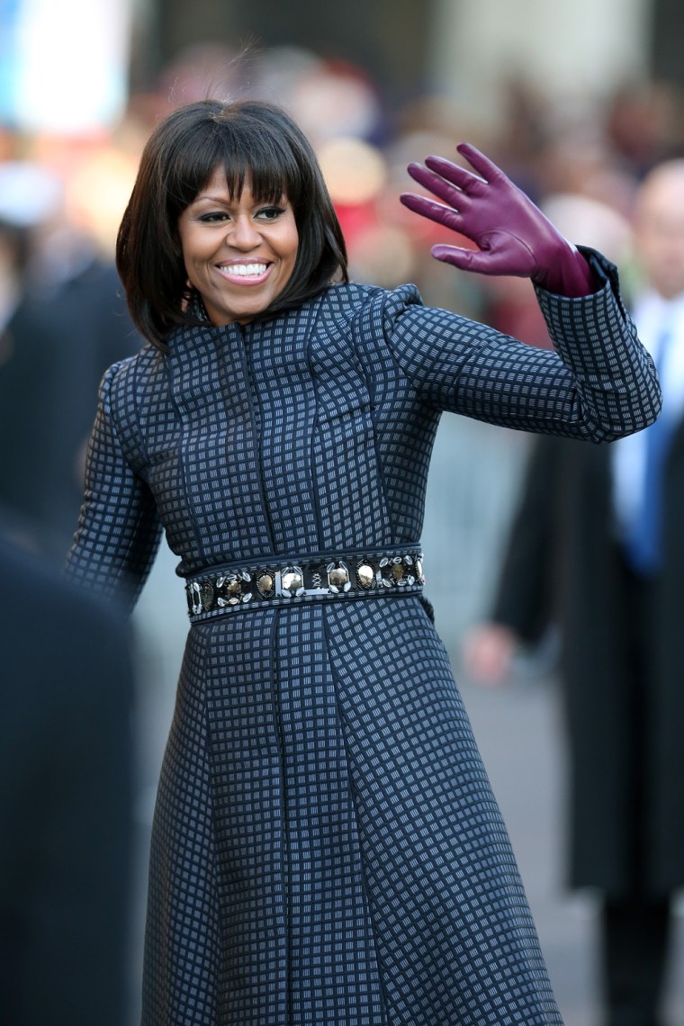 First lady Michelle Obama waves as the presidential inaugural parade winds through the nation's capital on Jan. 21, 2013. She's wearing a sophisticated blue Thom Browne coat, a bejeweled J. Crew belt and J.Crew gloves. Thom Browne, an American designer better known for his menswear, designed the coat based on the style of a man's silk tie.